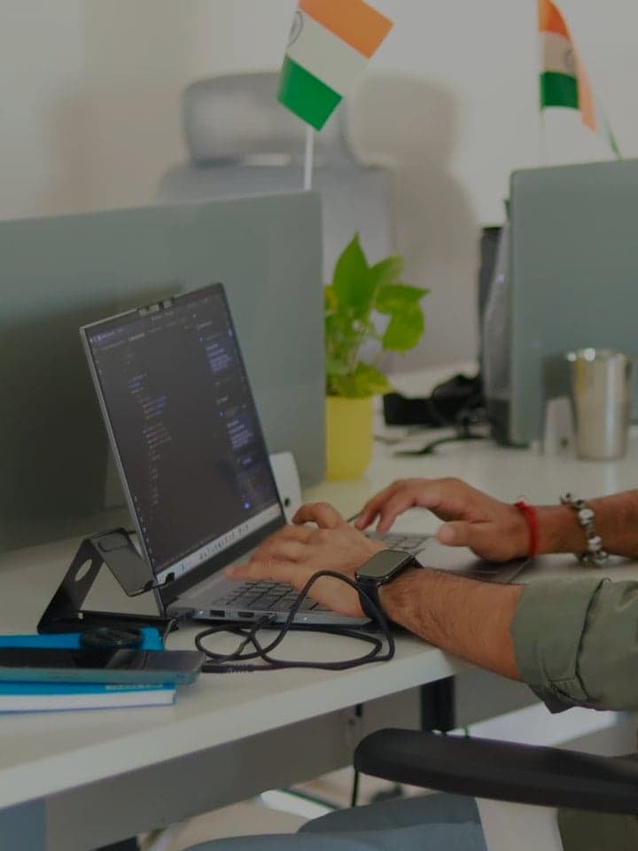 A developer writing code on a laptop in a small studio office.
